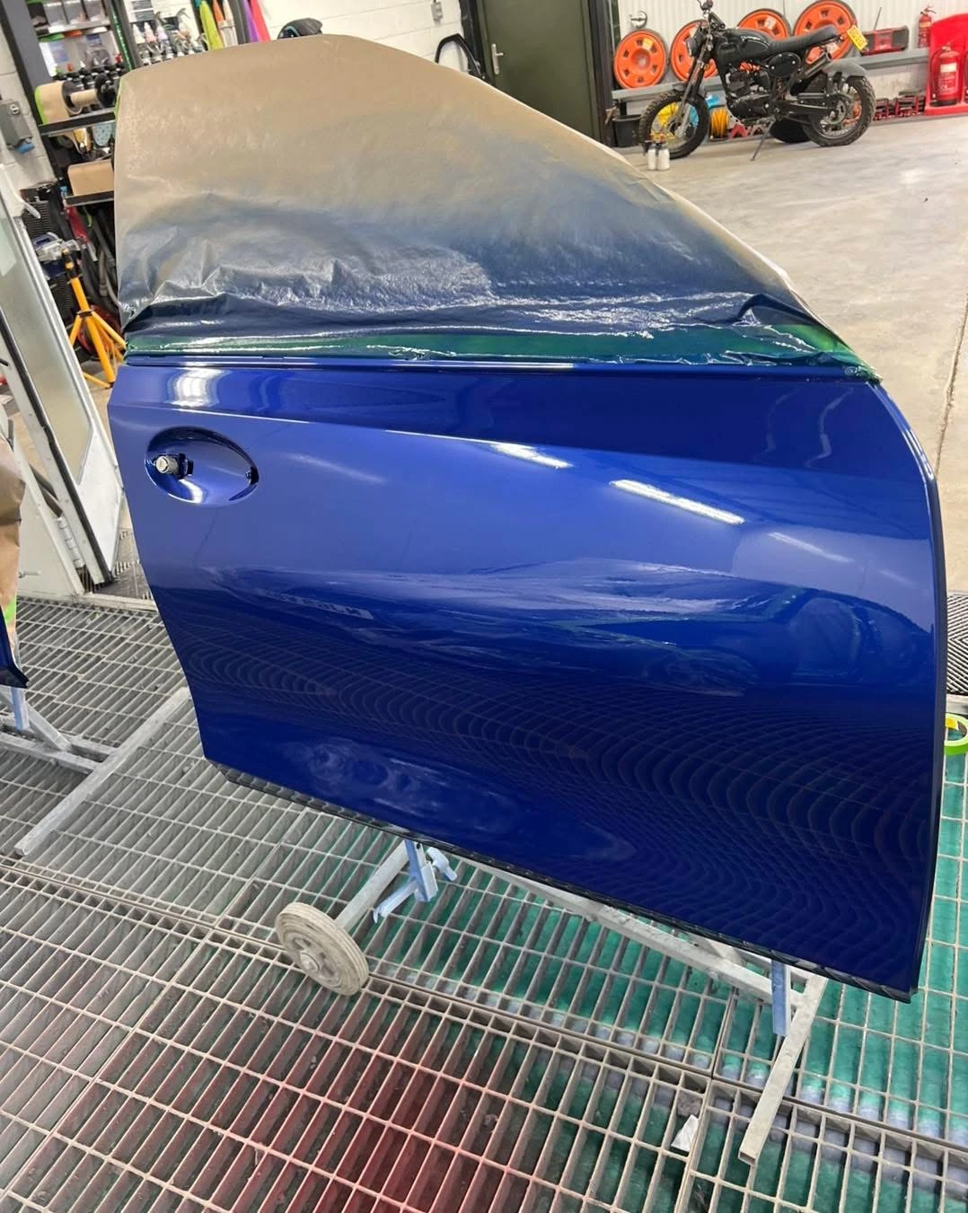 BMW 330i replacement front door painted blue on a stand
