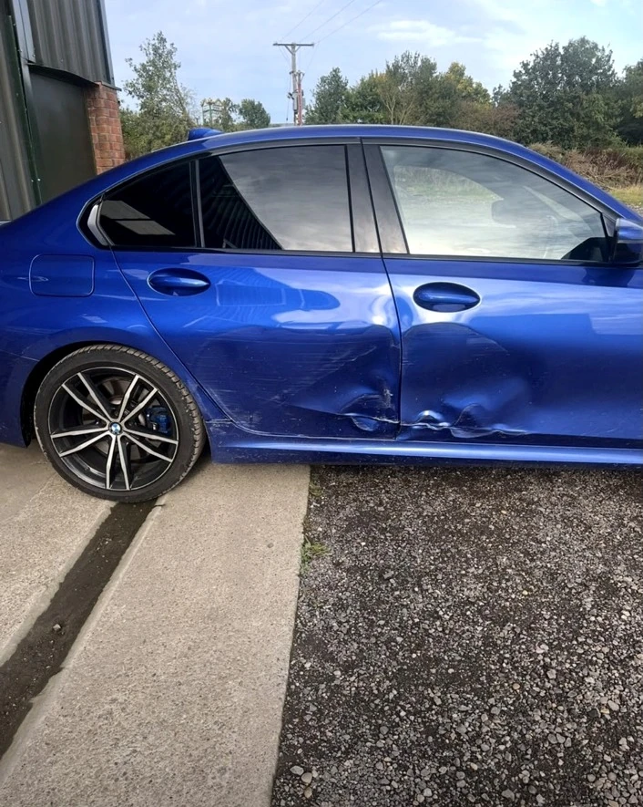 Blue BMW saloon before repair, with dent damage to both side doors