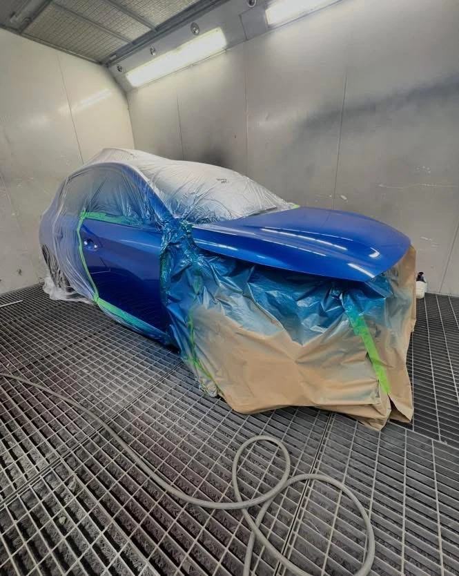 Peugeot 208 masked in the spray booth for paint blending on adjacent panels