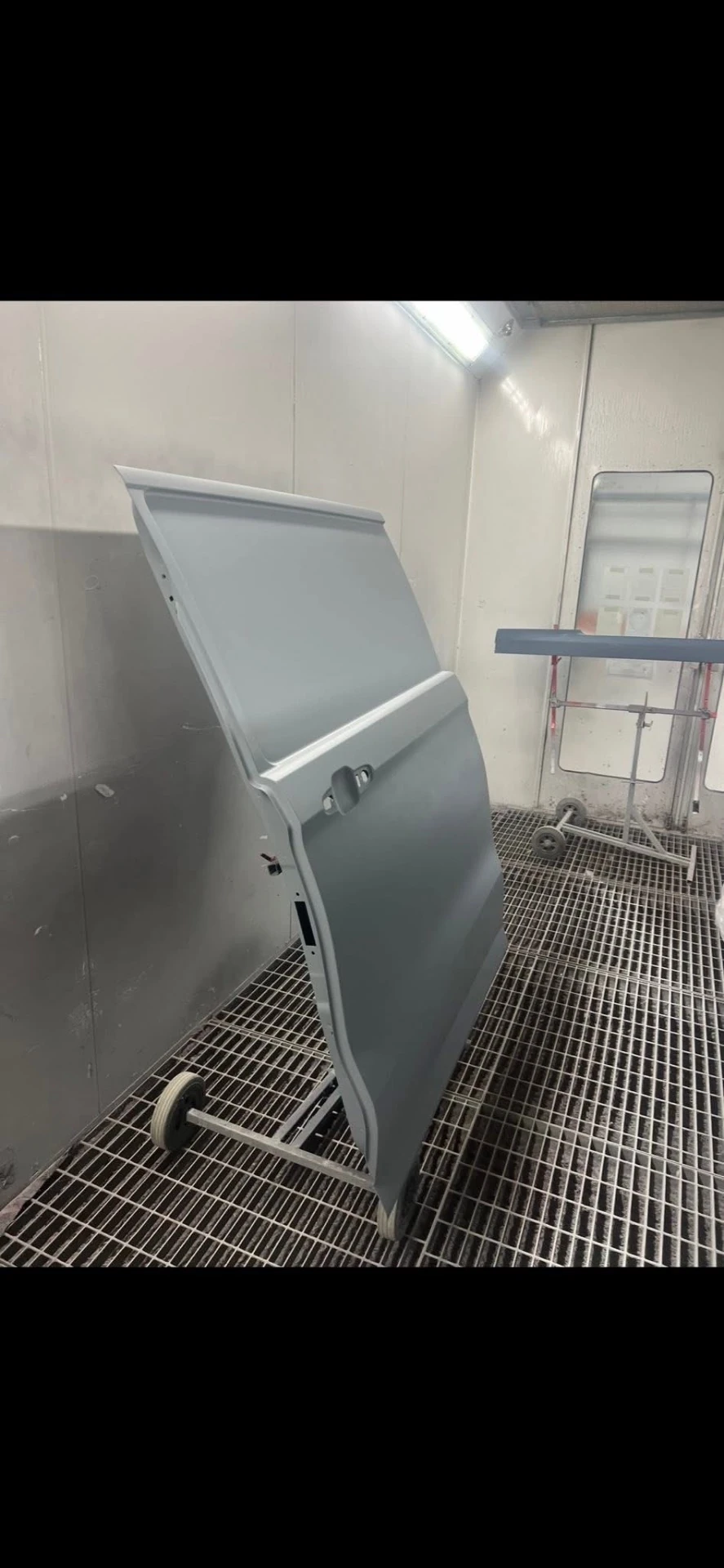 Ford Transit Custom replacement loading door prepared on a stand in the spray booth